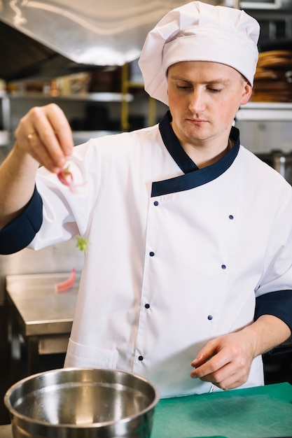 Free Photo | Cook putting vegetables in bowl for salad