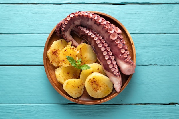 Premium Photo | Cooked octopus with potatoes, on black plate and blue ...