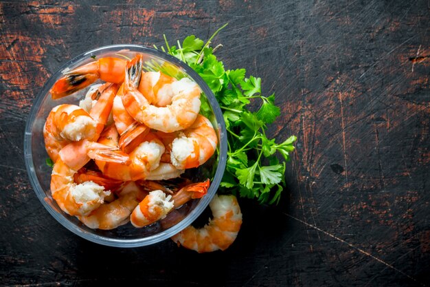 Premium Photo | Cooked shrimps in a bowl with greens. on dark rustic table
