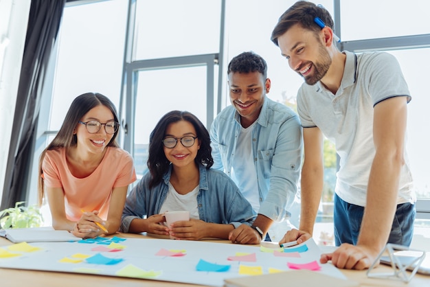 Premium Photo | Cooperative team. happy pleasant young people looking ...