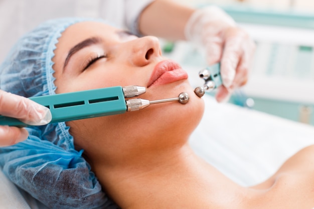 Premium Photo Cosmetology Beautiful Woman At Spa Clinic Receiving Stimulating Electric Facial
