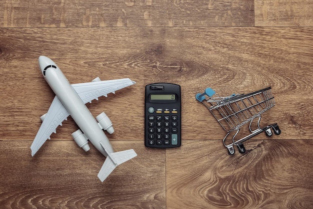 Premium Photo Cost Calculation Of Air Delivery Shopping Logistics Figurine Of Shopping Trolley Airplane Calculator On Wooden Floor