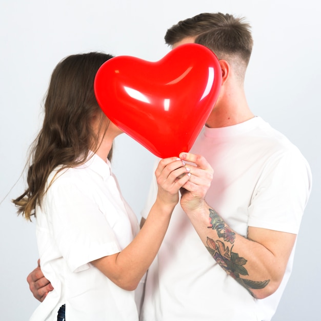 Free Photo Couple Covering Faces With Heart Balloon