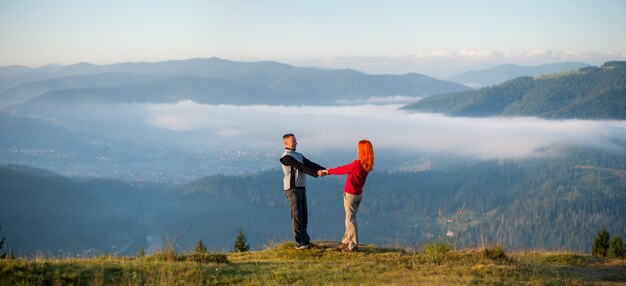 Premium Photo | Couple hikers holding hands and facing each other on a hill