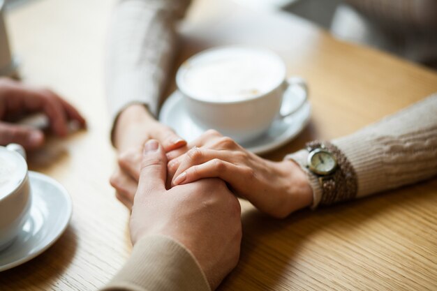 Couple hold hands drinking coffee in cafe | Premium Photo