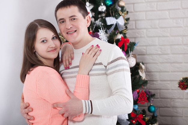 家で一緒にクリスマスを抱き締めて楽しんでいるカップル プレミアム写真