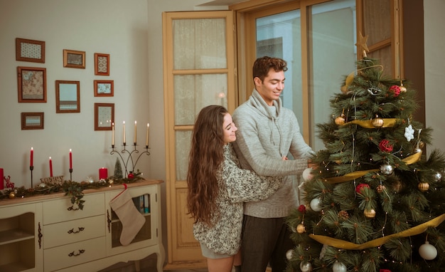 クリスマスの家を飾る間に抱き合っているカップル 無料の写真
