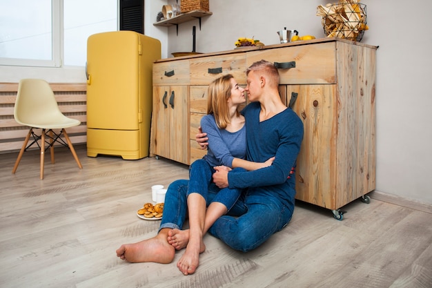 Couple Hugging While Sitting On The Kitchen Floor Photo Free Download