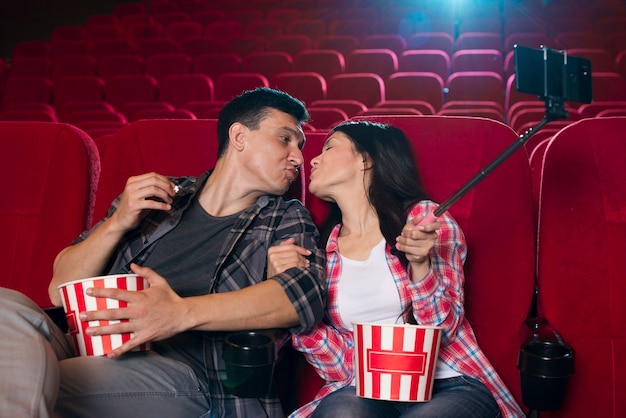 カップルがキスをし 映画館でselfieを引き継ぐ 無料の写真