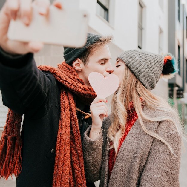 心の後ろにキスしてセルフをするカップル 無料の写真