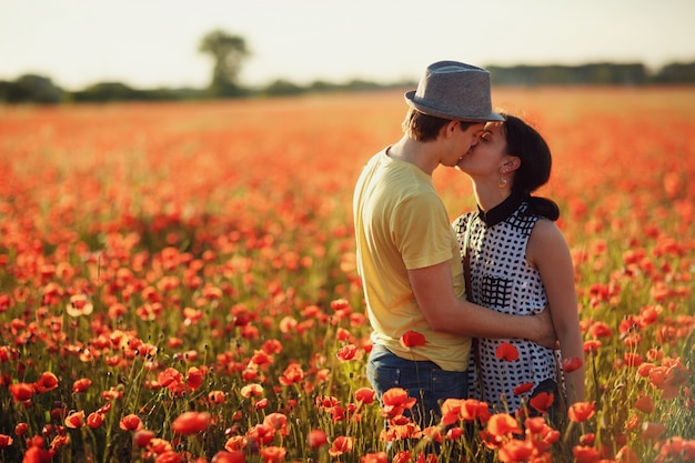 Couple kissing in a field of red flowers Photo | Premium Download