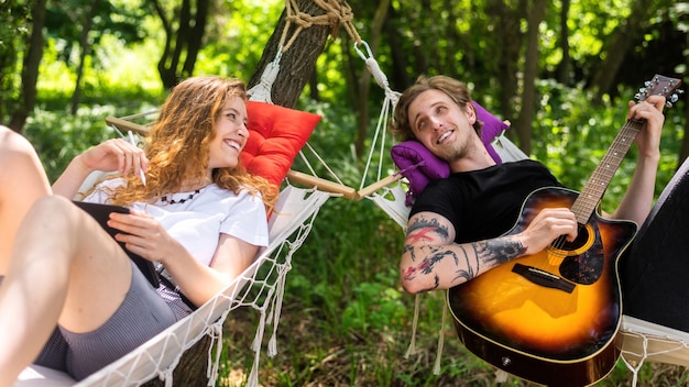 Premium Photo | Couple lying on hammocks young man is playing guitar