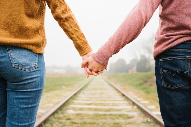 Couple Standing On Railroad Tracks And Holding Hands Photo