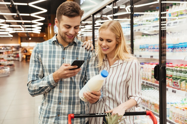 Couple in supermarket reading shopping list Free Photo