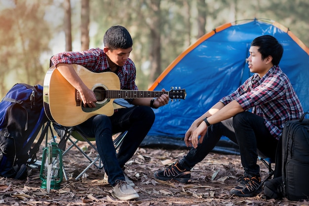 キャンプのアコースティックギターの時間を再生するカップルの観光客 プレミアム写真