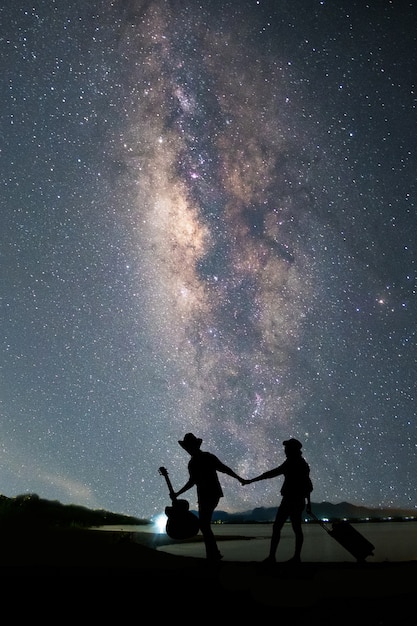 湖の近くに立っていて 天の川と星空を見ているカップルの旅行者 プレミアム写真