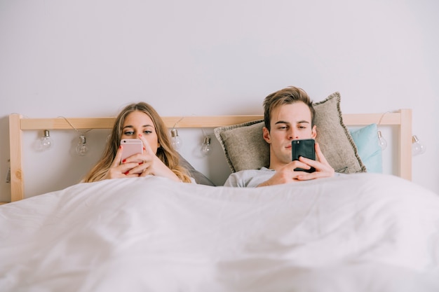 Couple using smartphones in bed Free Photo