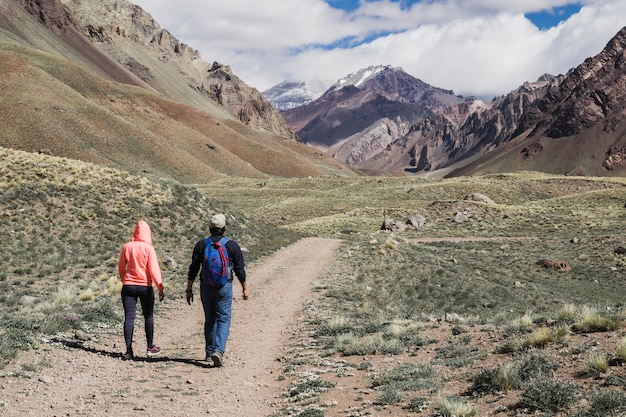 Couple walking on dirt track near mountain range | Free Photo