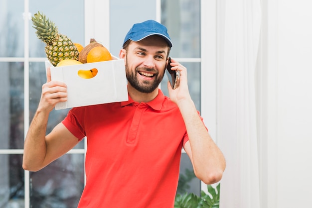 Courier with fruits speaking on phone Free Photo