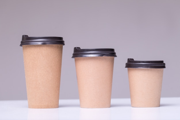 Covered paper coffee cups different sizes isolated on gray | Free Photo