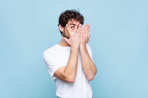 Premium Photo Covering Face With Hands Peeking Between Fingers With Surprised Expression And Looking To The Side