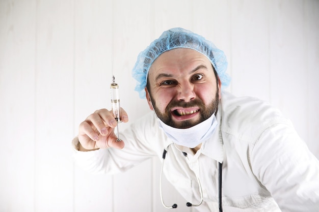 Premium Photo | Crazy bearded doctor in a white coat and an old syringe