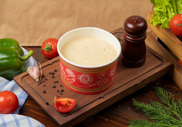 Cream mushroom soup in disposable cup bowl served with green vegetables. Free Photo