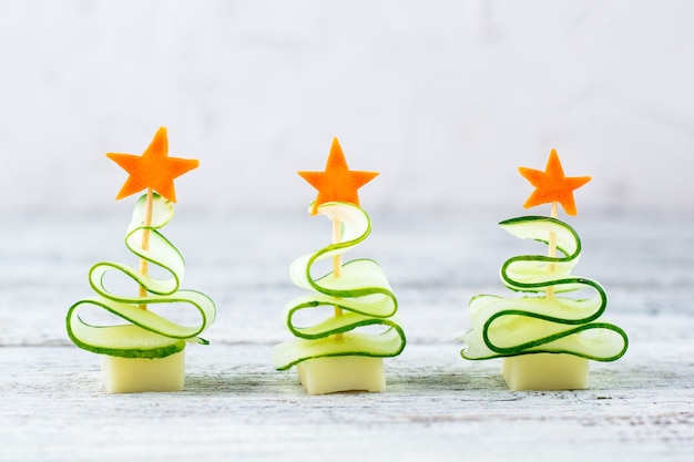 創造的なコンセプトは キュウリ チーズ ニンジンの星のクリスマスツリーを設定します コピースペースと灰色の背景に新年会のための面白い子供たちの食べ物 プレミアム写真