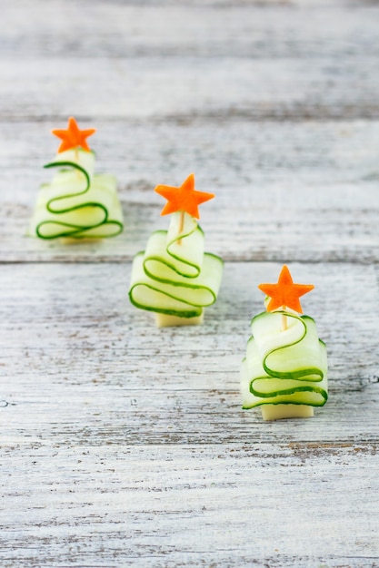 創造的なコンセプトは キュウリ チーズ ニンジンの星のクリスマスツリーを設定します コピースペースと灰色の背景に新年会のための面白い子供たちの食べ物 プレミアム写真