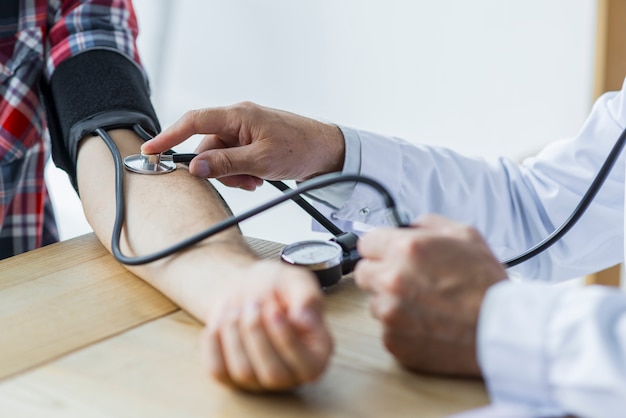 Crop doctor measuring blood pressure of patient Free Photo