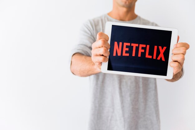 Crop guy holding tablet with netflix writing | Free Photo