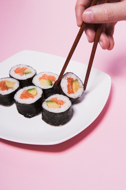 Crop hand taking sushi with chopsticks | Free Photo