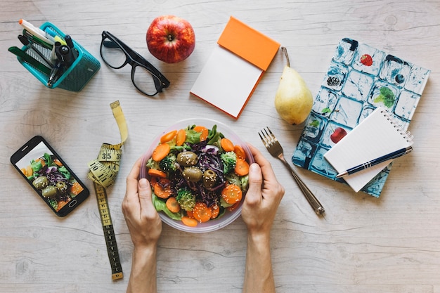 Free Photo | Crop hands holding bowl with salad in office