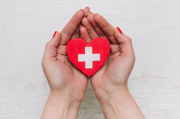 Crop hands holding heart with cross Free Photo