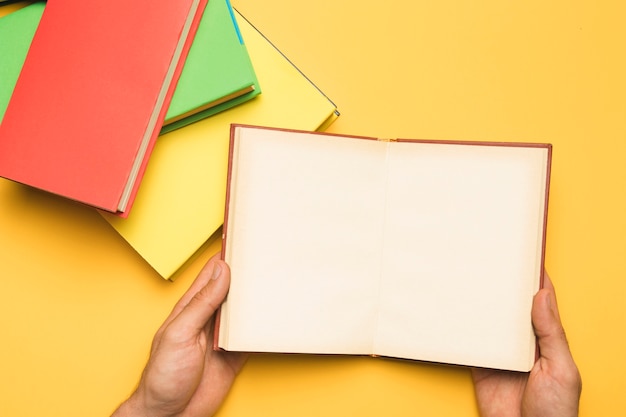 Crop person holding open notebook near stack of books Free Photo