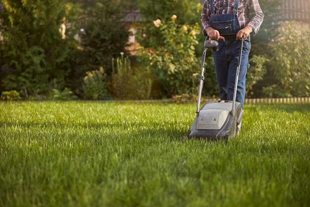 Premium Photo | Cropped photo of a working man moving a lawn with a ...