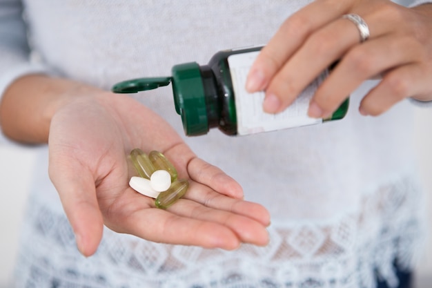 Cropped View of Woman Pouring Pills From Bottle Free Photo