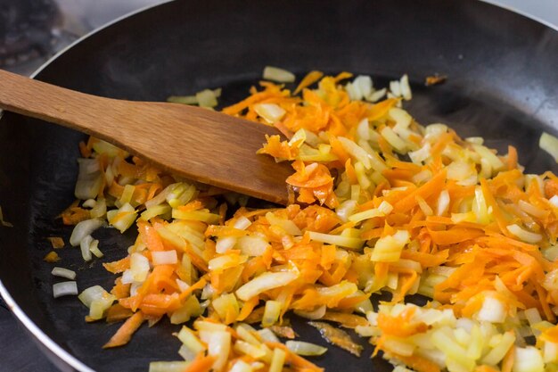 Premium Photo | Crushed onions and carrots in a frying pan and wooden ...