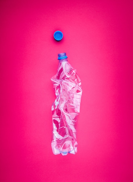 鮮やかなピンクのおしゃれな背景に押しつぶされたペットボトルのクローズアップ プレミアム写真