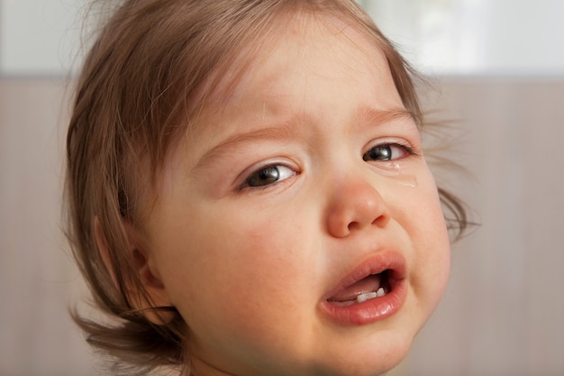 目に涙を浮かべて泣いている赤ちゃん プレミアム写真
