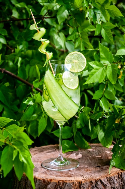 Premium Photo Cucumber Water Or Lemonade In Glass With Lime On Wooden Stump In Forest Refreshing Summer Drink Concept