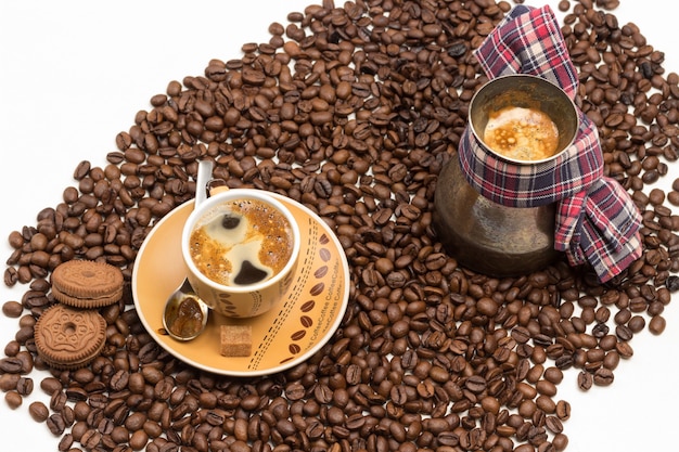 Чашка кофе с пеной и турка с кофе с большим количеством кофейных зерен .