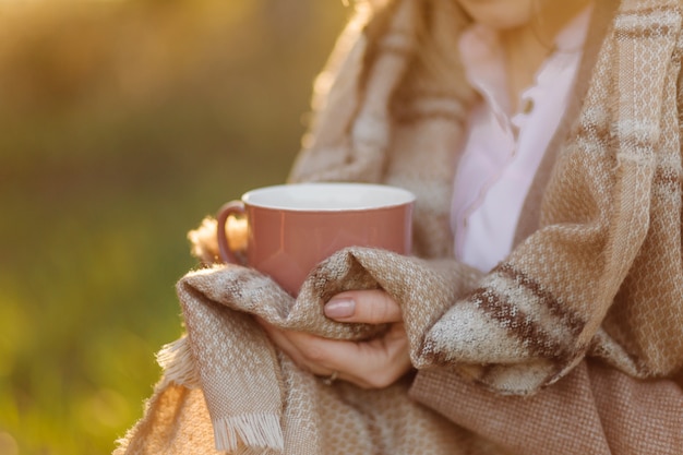 Cup on sunset in hand young girl covered with a blanket Free Photo