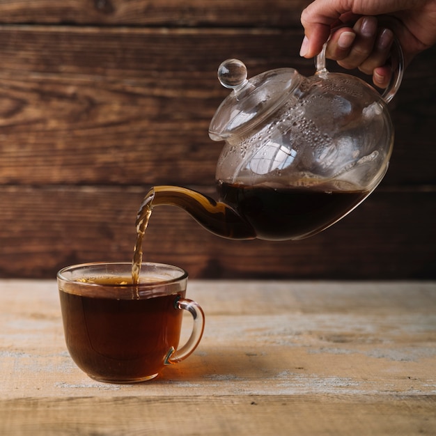 Cup of warm tea being filled from a teapot | Free Photo