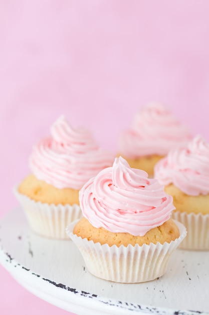 パステル調のピンクの背景にピンクのバタークリームで飾られたカップケーキ プレミアム写真