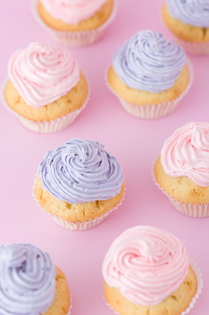 ピンクと紫のバタークリームパステルピンクの背景上面に立っているとカップケーキ プレミアム写真