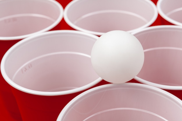 カップと赤い表面にプラスチック製のボール ビールポンゲーム プレミアム写真