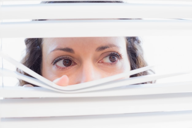 Premium Photo | Curious woman looking through blinds