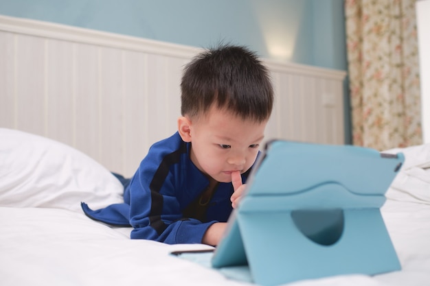 かわいいアジアの3 4歳の幼児の男の子の子供がゲームをプレイしている間 漫画を見ている タブレットpcコンピューターを使用して ガジェット中毒の子供たち 子供のためのタブレットを学ぶ 幼児教育玩具のコンセプト プレミアム写真