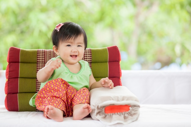 Cute Asian Baby Girl In Thai Traditon Dress Sitting With Pillow